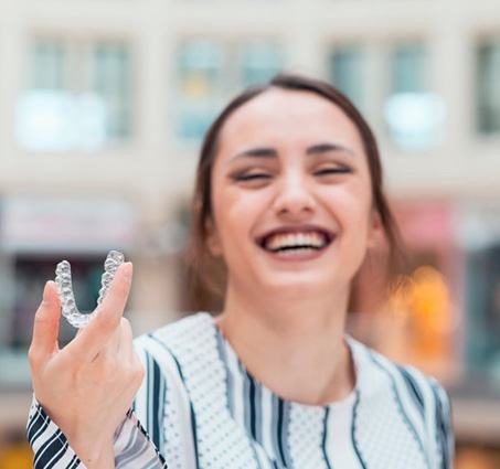 Woman out and about showing her removable Invisalign tray