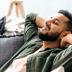 a man relaxing on his couch and smiling comfortably